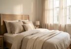 Chambre lumineuse avec literie en lin beige naturel, tête de lit en bois et lumière douce du matin